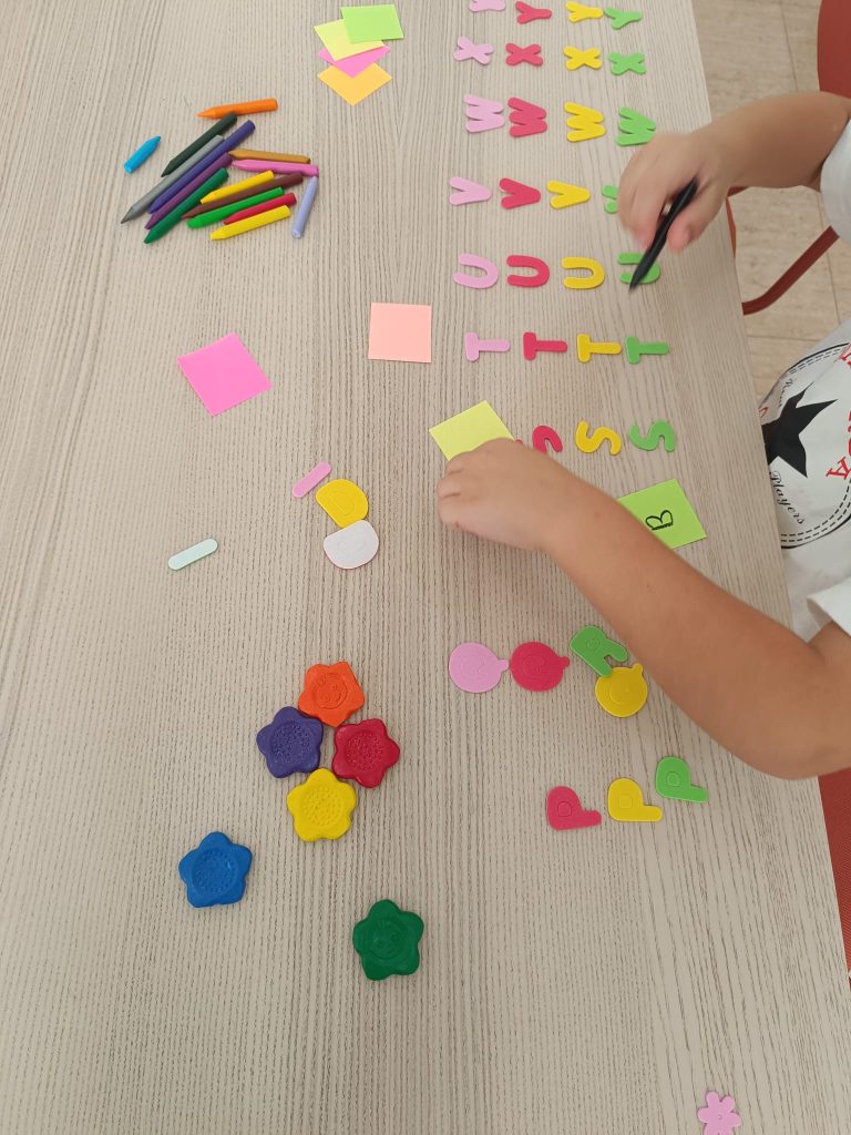 Peque creando con formas y letras de colores sobre la mesa