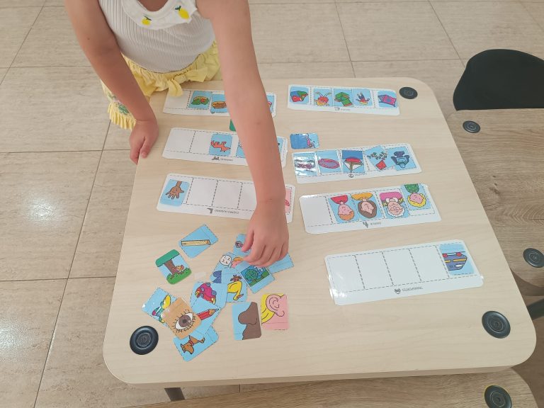 Niña emparejando tarjetas de lectoescritura sobre la mesa